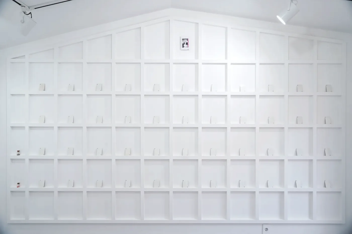 긁어낸 상징 — playing cards with their patterns scratched away, arranged on a white wall