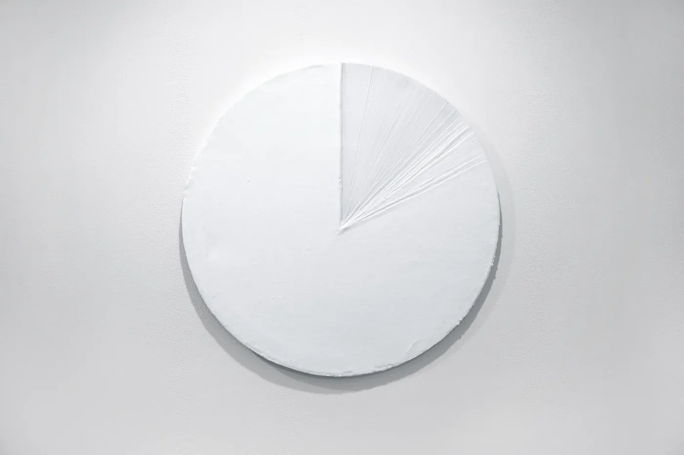 0+0+0+0+0+0+0+0+0+0+0+0=1 — a white circular canvas built up with layers of gesso, one wedge of radiating lines