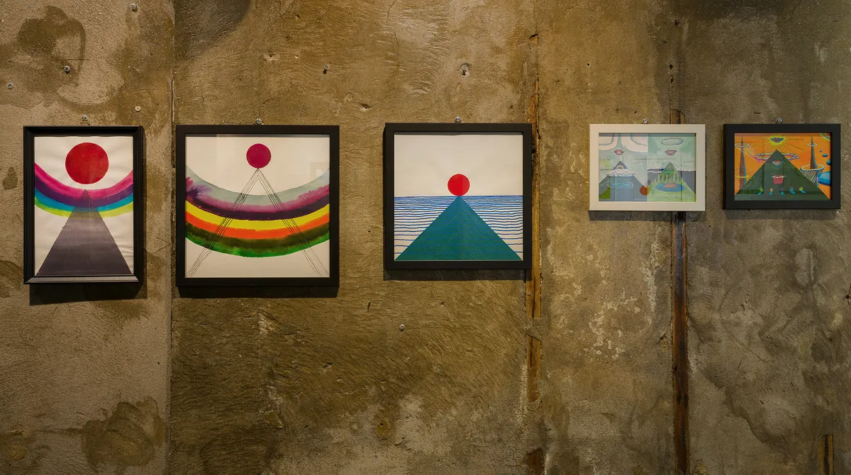 Installation view — sun-and-mountain works on a concrete wall