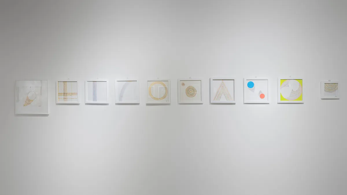 Installation view — row of small framed drawings on a white wall