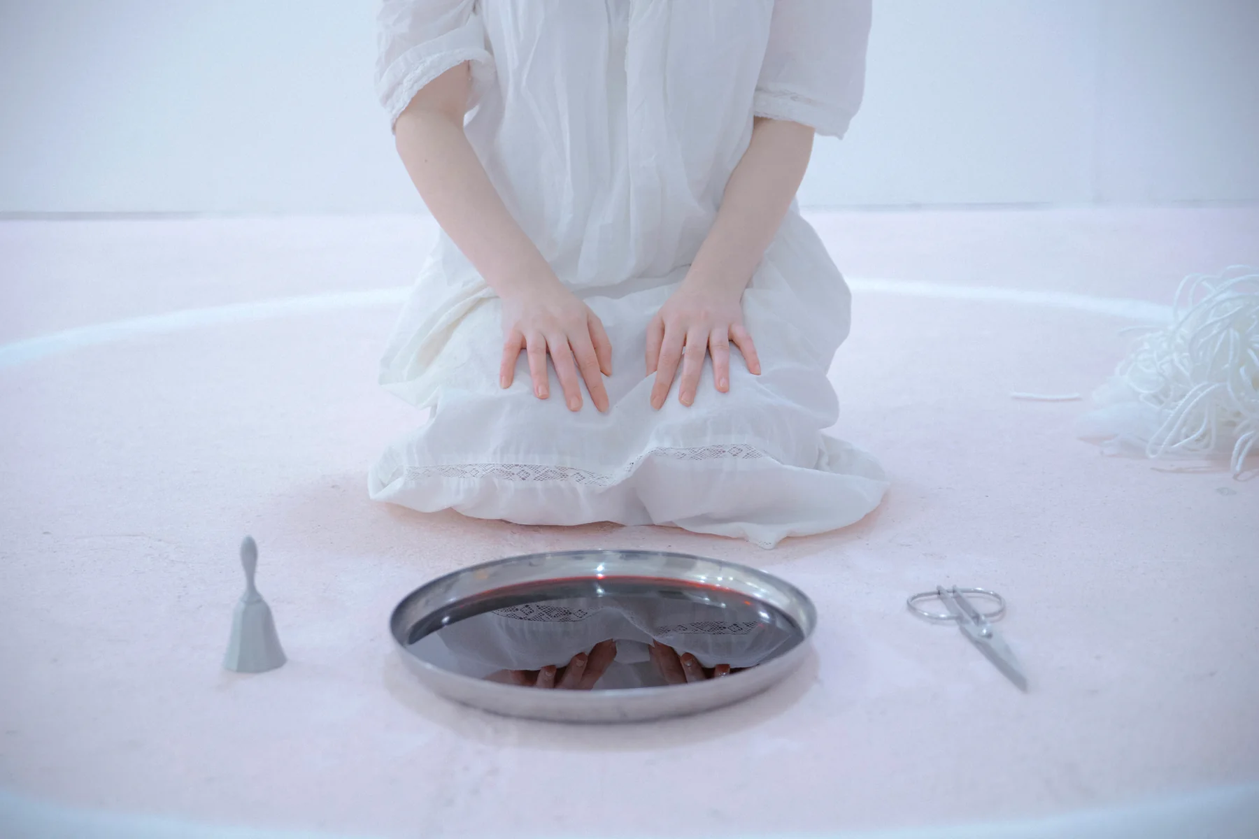 흰 옷을 입고 흰 모래 원 안에 무릎 꿇은 영안 — 앞에 포도주가 담긴 대야, 곁에 은색 종과 가위